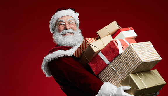 Weihnachtsmann h&auml;lt viele Geschenke und grinst