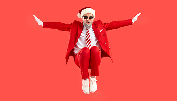 Mann im Weihnachtsmann-Anzug und Sonnenbrille springt in die Luft