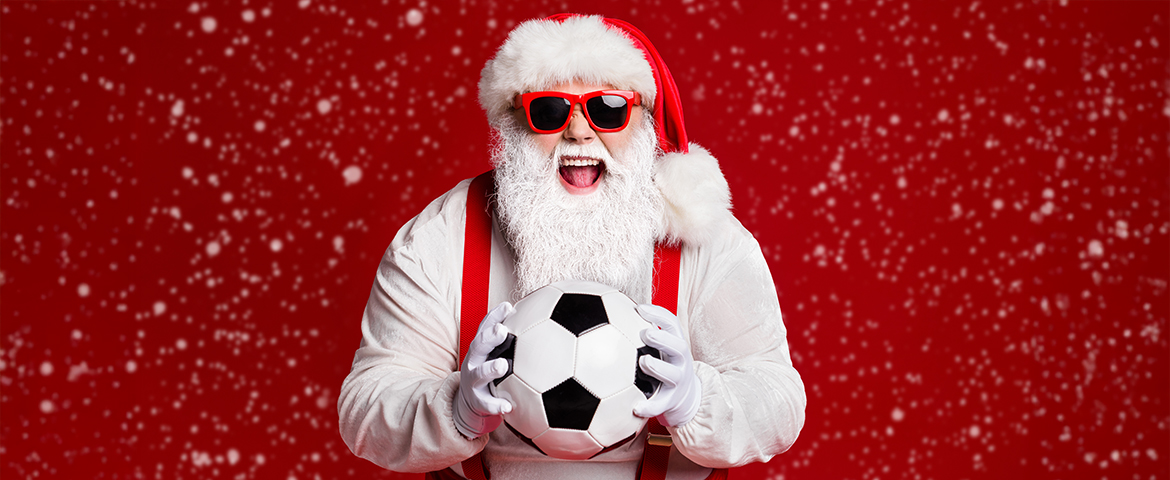 Weihnachtsmann h&auml;lt Fu&szlig;ball in den H&auml;nden und freut sich