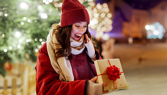 Frau schaut freudig in eine ge&ouml;ffnete Geschenkbox
