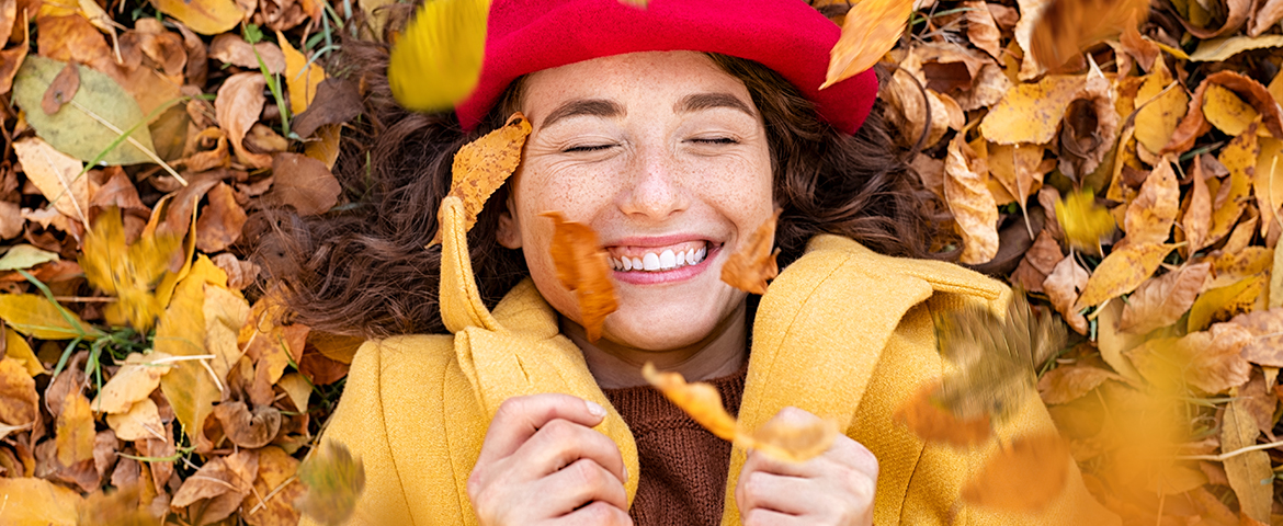 Frau liegt lächelnd im Herbstlaub