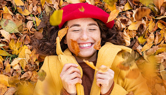 Frau liegt lächelnd im Herbstlaub