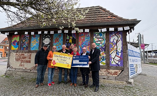 Die Vereinsvorsitzende mit dem symbolischen Spendenscheck vor dem Tunnelh&auml;uschen in Stendal