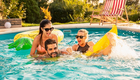 Eine Mann und zwei Frauen haben Badespaß im Swimmingpool