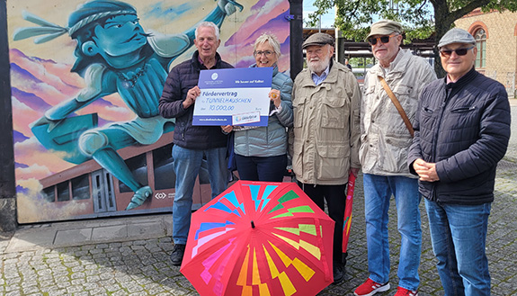 F&uuml;nf Personen mit symbolischen F&ouml;rderscheck vor Tunnelh&auml;uschen