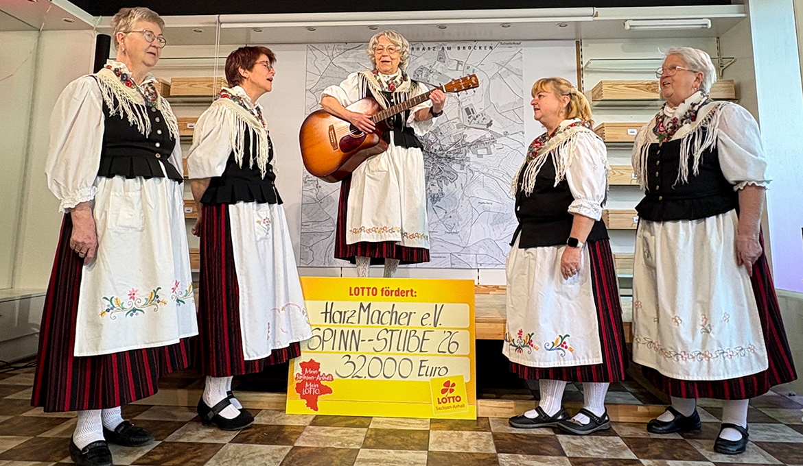 F&uuml;nf Frauen in Trachtenkleidung stehen um einen symbolischen Lotto-Scheck herum und singen. von links: _Christina Hundt, Susanne Schneider-Madsack, Christel Liebetruth, Karin Garcke, Heide Witteborn Kopie