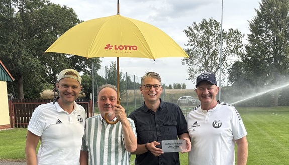 Jens u. Gero Stürzebecher, Rainer Jung, Andreas Lemke vom Ummendorfer Sportverein e. V.  mit Regenschirm vor dem neuen Rasenbewässerungssystem