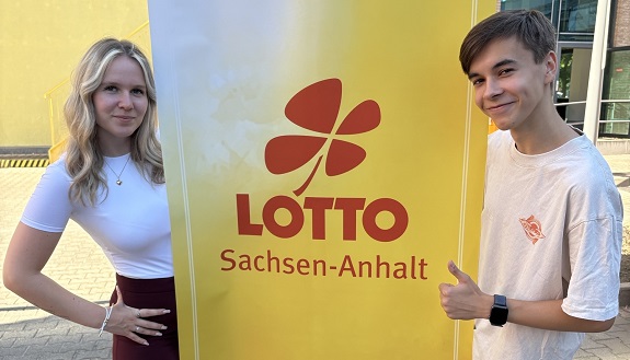 Azubis Lea Maria Luksche und Nils Leopold vor Banner von LOTTO Sachsen-Anhalt