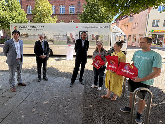 F&ouml;rderbescheid-&Uuml;bergabe mit altem B&uuml;cherbus im Hintergrund