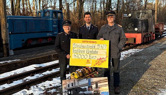 Drei Mitglieder vom Traditionseisenbahnverein mit dem symbolischen Scheck von Lotto