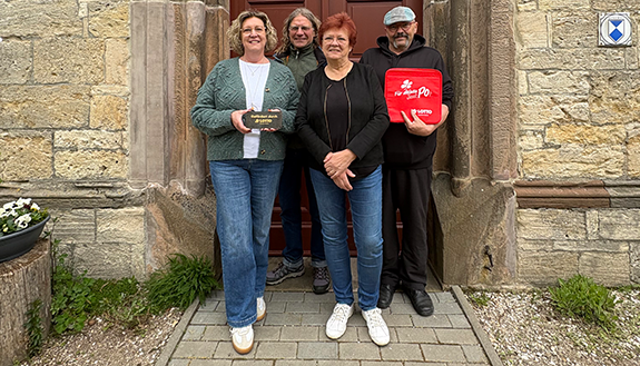 Vereinsvorsitzende Silvia B&ouml;hland und Mitglieder des F&ouml;rdervereins vor Kirchet&uuml;r mit Lotto-F&ouml;rdertafel in der Hand