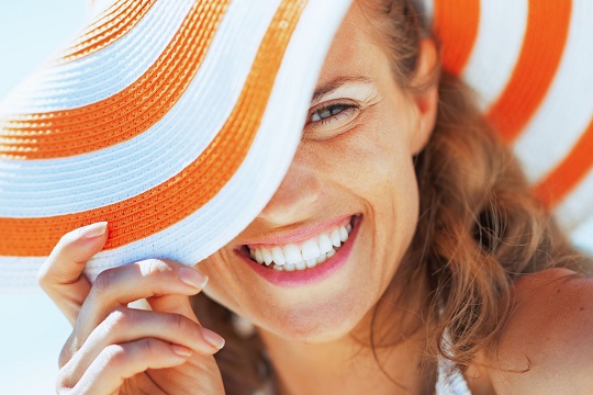Junge Frau lächelt mit Sommerhut