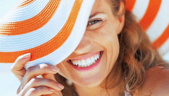 Junge Frau lächelt mit Sommerhut