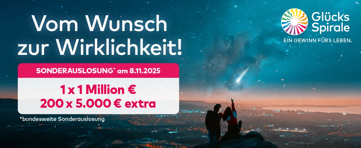 Ein Pärchen schaut den Sternenhimmel über einer großen Stadt am Meer von einem Hügel aus an