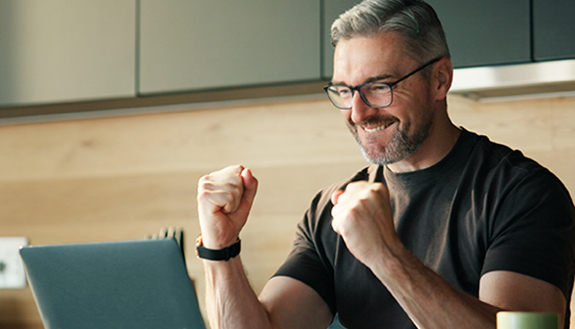 Mann aus Halle  gewinnt 83000 Euro bei Eurojackpot, sitzt am Tisch vor einem Laptop und jubelt