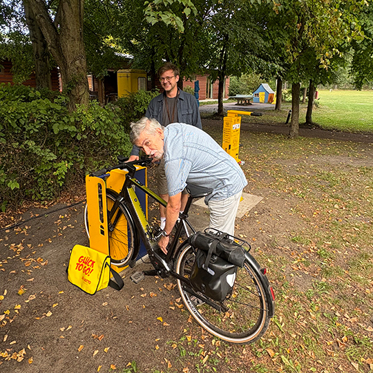 Rüdiger Schröter und Wolf-Michael Hartlapp an Fahrradservice- und Ladestation auf dem Zeltplatz Friedensau