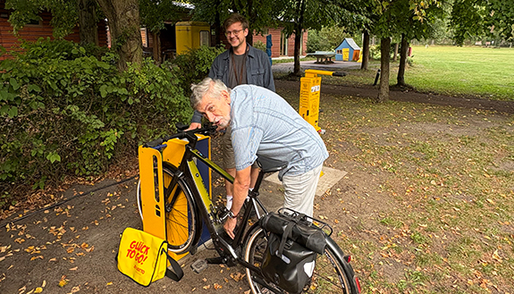 Rüdiger Schröter und Wolf-Michael Hartlapp an Fahrradservice- und Ladestation auf dem Zeltplatz Friedensau