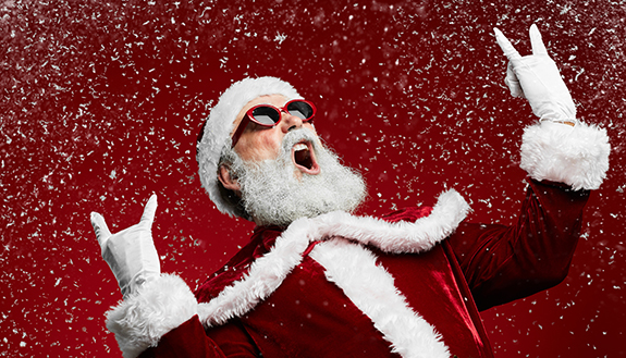 Weihnachtsmann mit Sonnenbrille jubelt in Rocker-Pose